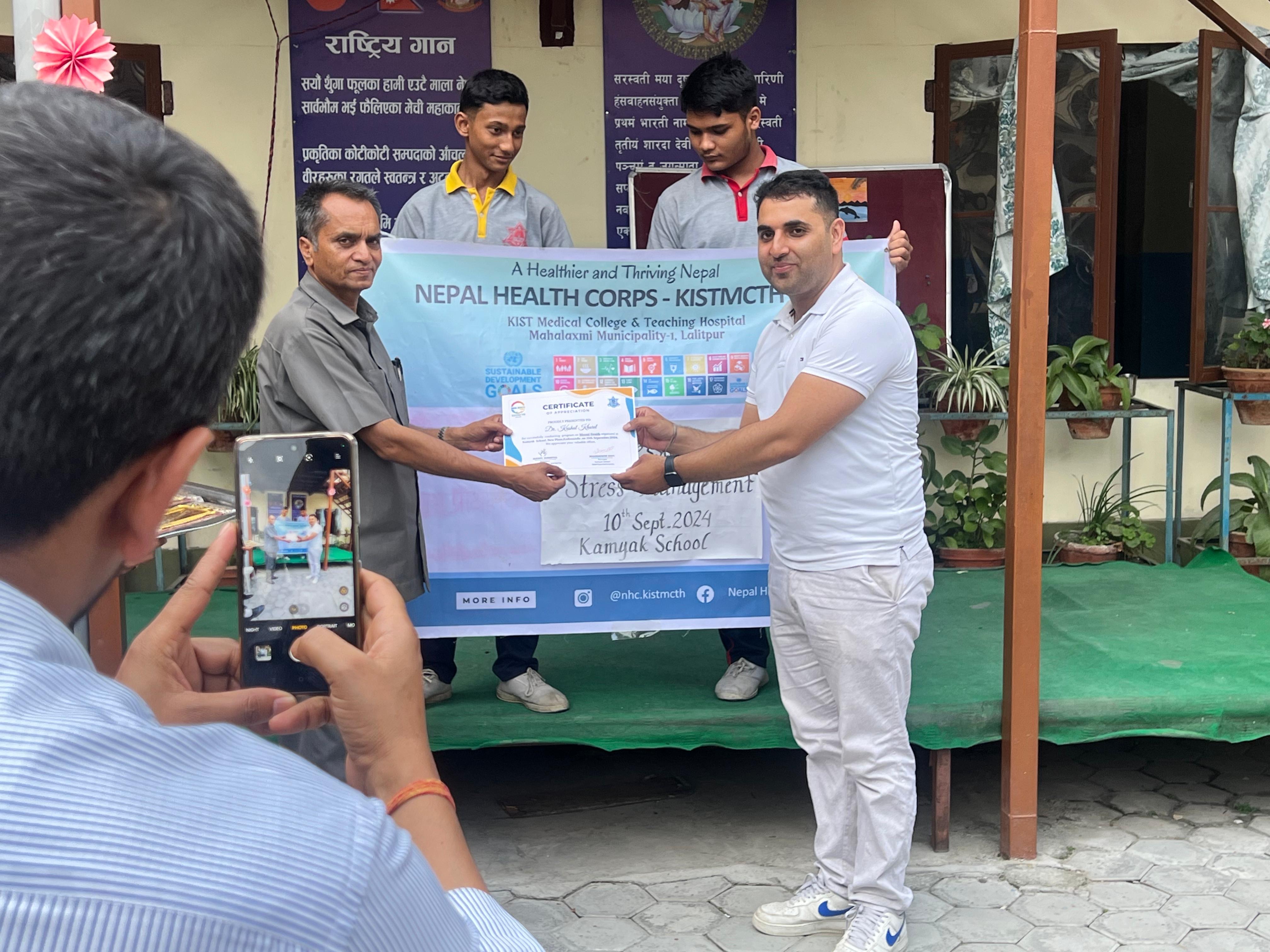 Dr. Kushal Kharel receiving recognition during a Nepal Health Corps school outreach programme